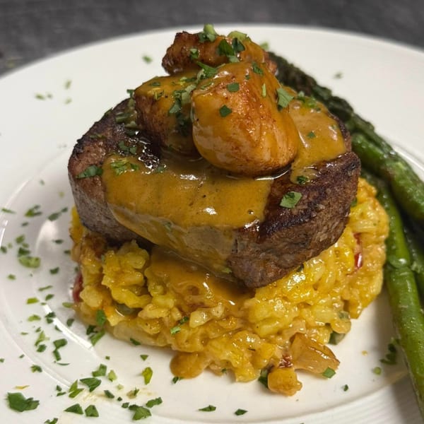 Scratch Steakhouse And Lounge's filet mignon with mushrooms, sauce, risotto, and asparagus on a white plate.